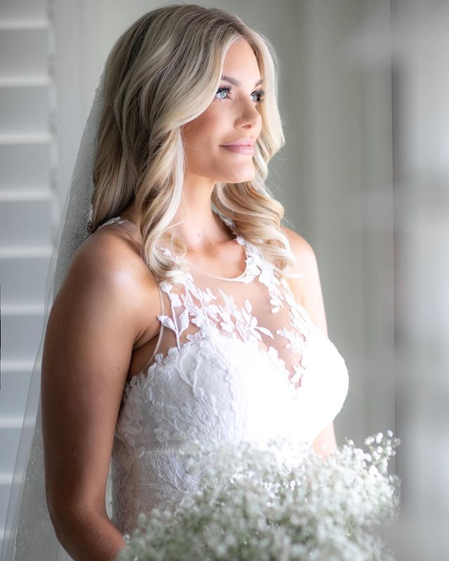 Lauren Wirkus in a white bridal dress holding white flowers.